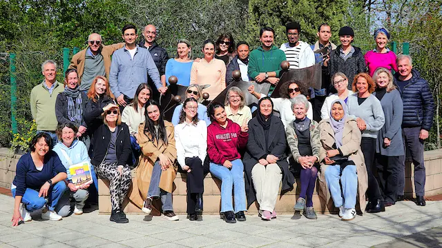 Rassemblement des bénévoles et apprenants du projet Espoir 13 souriant en extérieur devant un bâtiment.